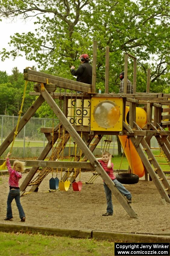 Kids play on the playground while a spotter watches the race from the top of the play structure