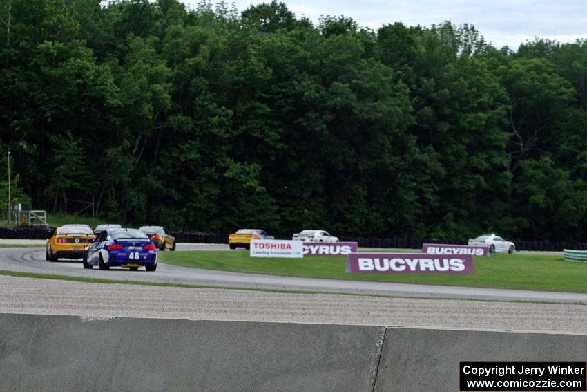 The field follows the pace car through the carousel during an early yellow.