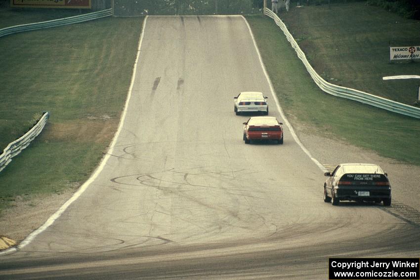 Three cars head out of turn 5 uphill toward 6