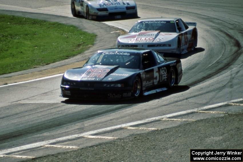 Darin Brassfield's and Chris Kneifel's Olds Cutlass Supremes ahead of Bob Sobey's Chevy Camaro