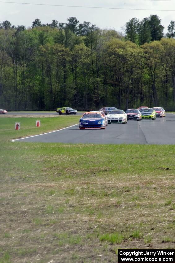 Derek Thorn's Ford Fusion leads the field into turn 4 on lap one.