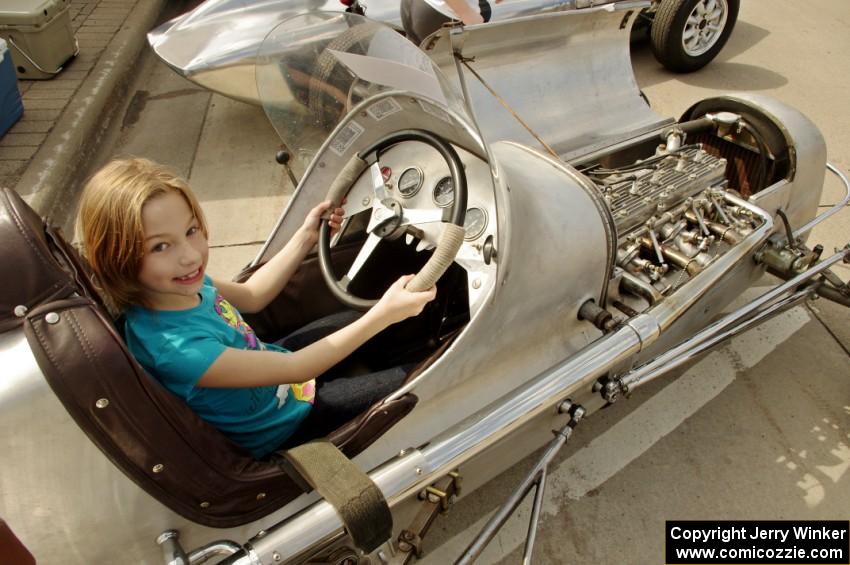 A spectator fits into an old midget racer on display.