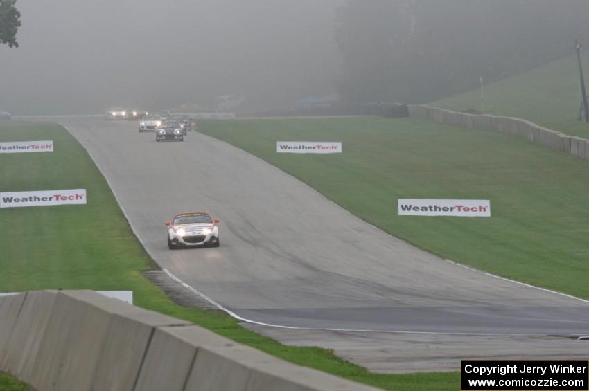 MX-5s head downhill into turn 8 in the thick fog.