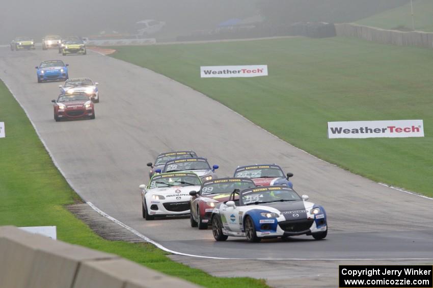 MX-5s head downhill into turn 8 in the thick fog.