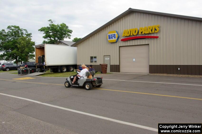 Mark Utecht drives his pit golf cart down the paddock road.