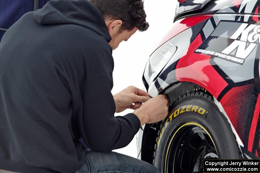 Josh Robinson makes ziptie repairs to the bumper of his Nissan 350Z.