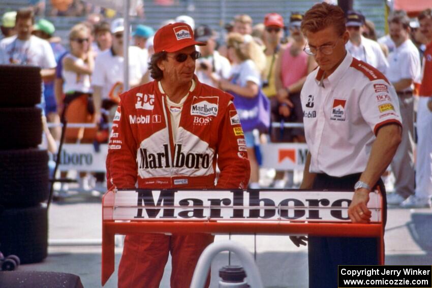 Emerson Fittipaldi and an aerodynamicist discuss setup in the paddock.