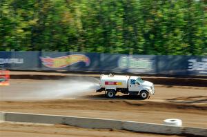 A water truck sprays down the track surface.