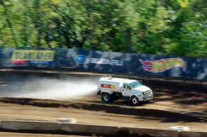 A water truck sprays down the track surface.