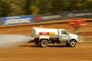 A water truck sprays down the track surface.