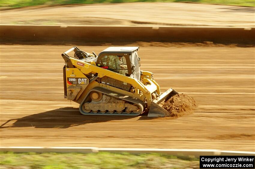 A small bulldozer helps smooth out the track surface.