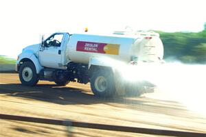 A water truck sprays down the track surface.