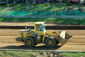 A front-end loader moves dirt to help smoothen out the track surface.