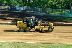 A road grader smooths out the track surface.