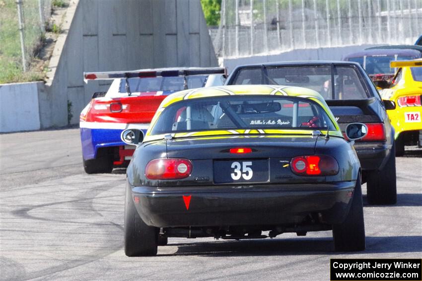 Dan Little's American Sedan Ford Mustang and Dan Corgard's Spec Miata Mazda Miata head for the track exit.