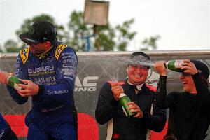 Javier Olivares and K.J. Miller spray champagne on Travis Pastrana on the winner's podium.