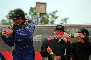 Javier Olivares and K.J. Miller spray champagne on Travis Pastrana on the winner's podium.