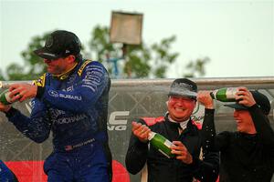 Javier Olivares and K.J. Miller spray champagne on Travis Pastrana on the winner's podium.