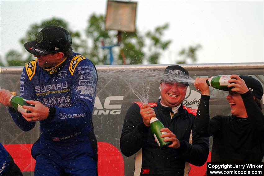 Javier Olivares and K.J. Miller spray champagne on Travis Pastrana on the winner's podium.