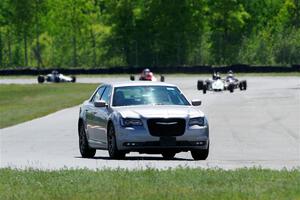 A Chrysler 300 paces the vintage formula car field.