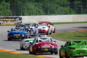 A train of Mazda MX-5 Cups head through the kink.