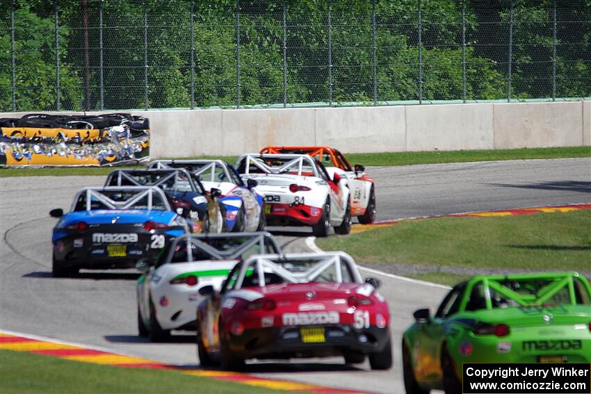 A train of Mazda MX-5 Cups head through the kink.