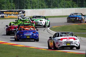 A train of Mazda MX-5 Cups head through the kink.
