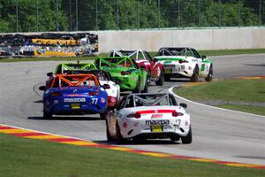 A train of Mazda MX-5 Cups head through the kink.
