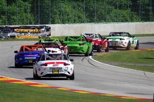A train of Mazda MX-5 Cups head through the kink.
