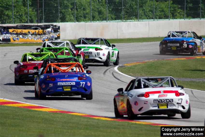 A train of Mazda MX-5 Cups head through the kink.