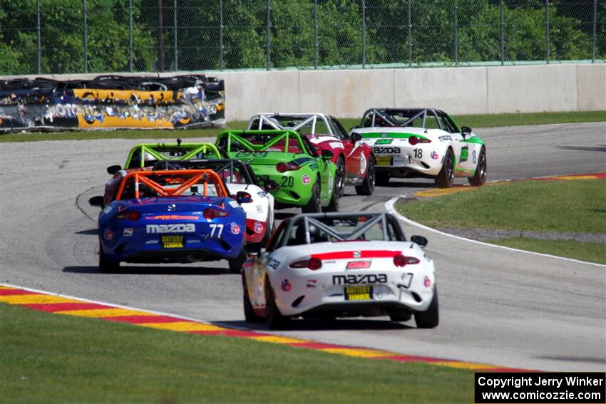 A train of Mazda MX-5 Cups head through the kink.