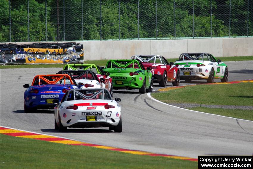 A train of Mazda MX-5 Cups head through the kink.