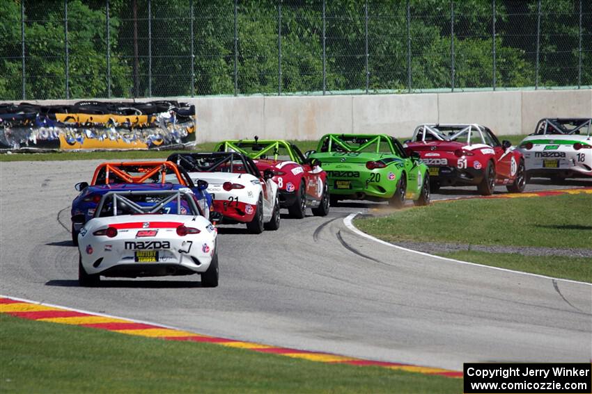A train of Mazda MX-5 Cups head through the kink.