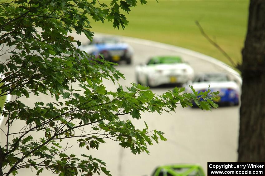 Three unknown Mazda MX-5 Cups head uphill through turn 13.