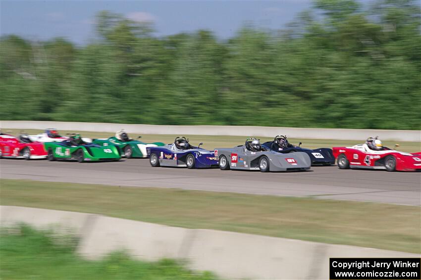 Spec Racer Ford 3s file into turn one on the first lap.