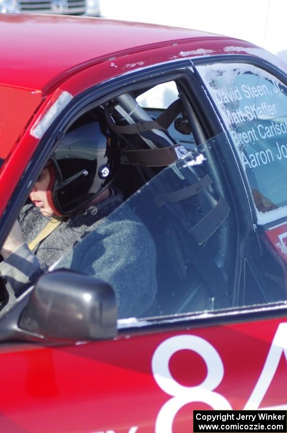 Brent Carlson straps into the driver's seat of the #84 Subaru Impreza